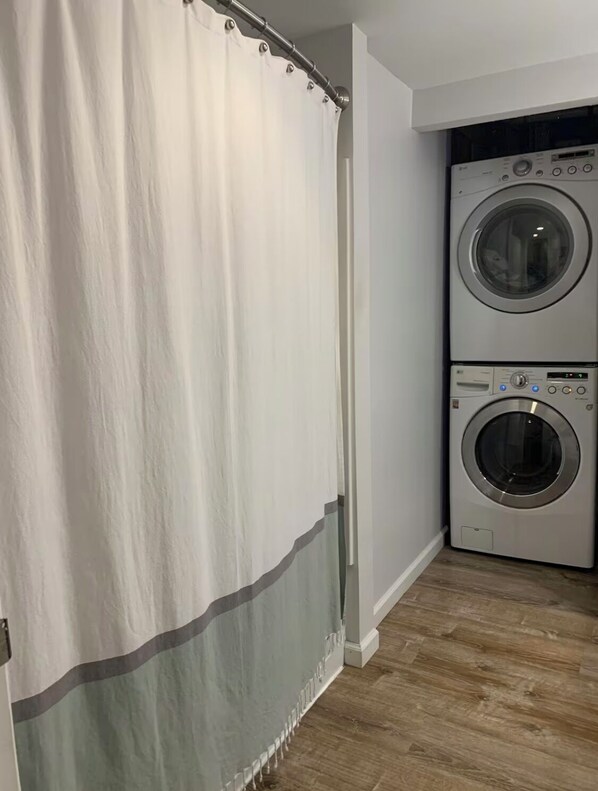A laundry room with two stacked front-loading washing machines and a white shower curtain with a gray stripe. - We Are…..2 miles from Beaver Stadium! (State College)