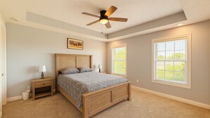 Ein Schlafzimmer mit einem hölzernen Bett, zwei Nachttischen, einem Deckenventilator und zwei Fenstern mit Jalousien.