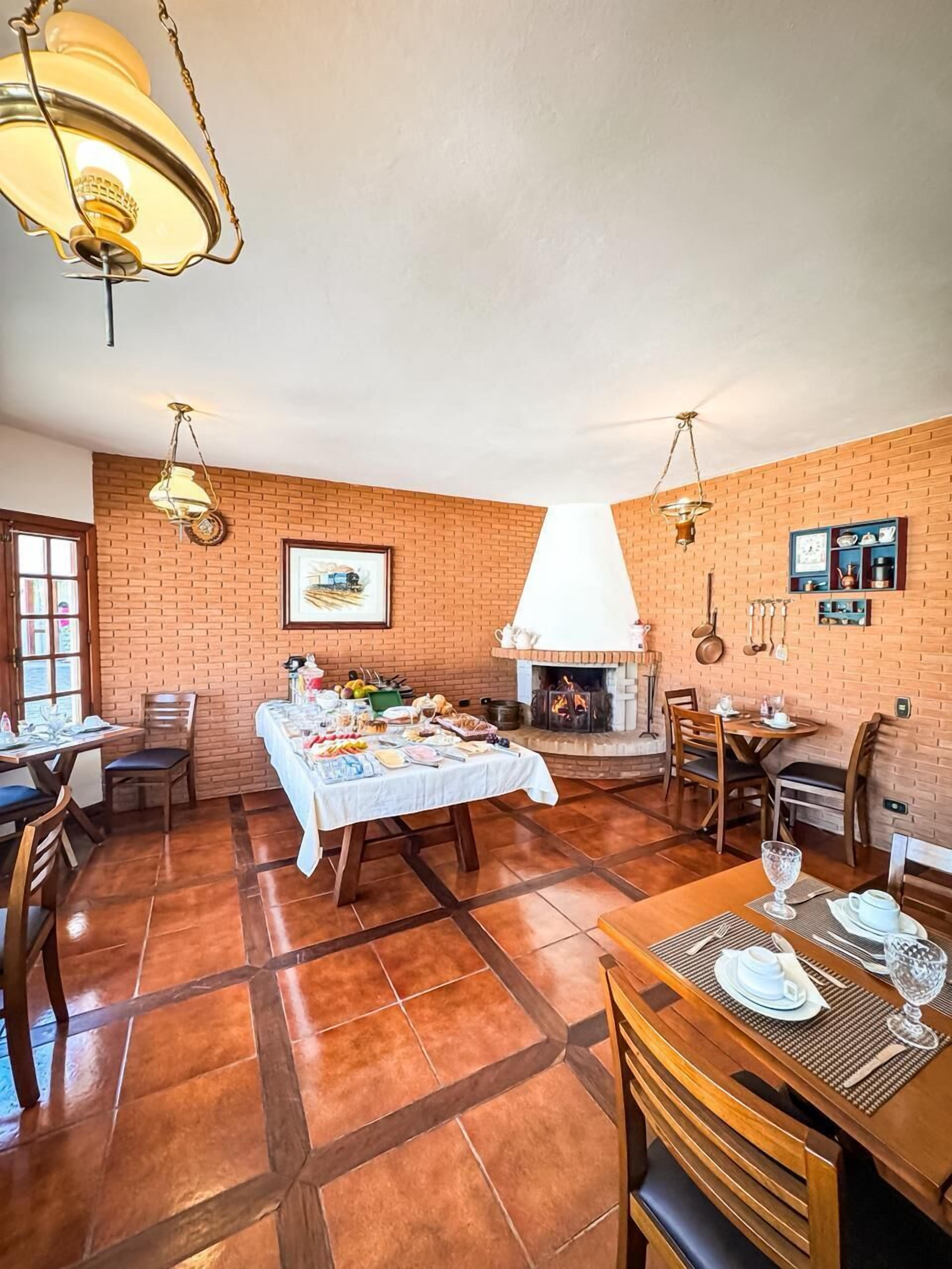 A dining area with brick walls, a fireplace, and a table set for a meal.