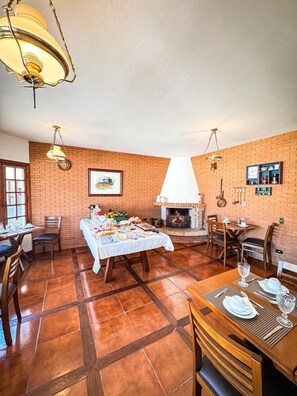 A dining area with brick walls, a fireplace, and a table set for a meal. - Pousada La Bella Campos do Jordão  (Campos do Jordao)