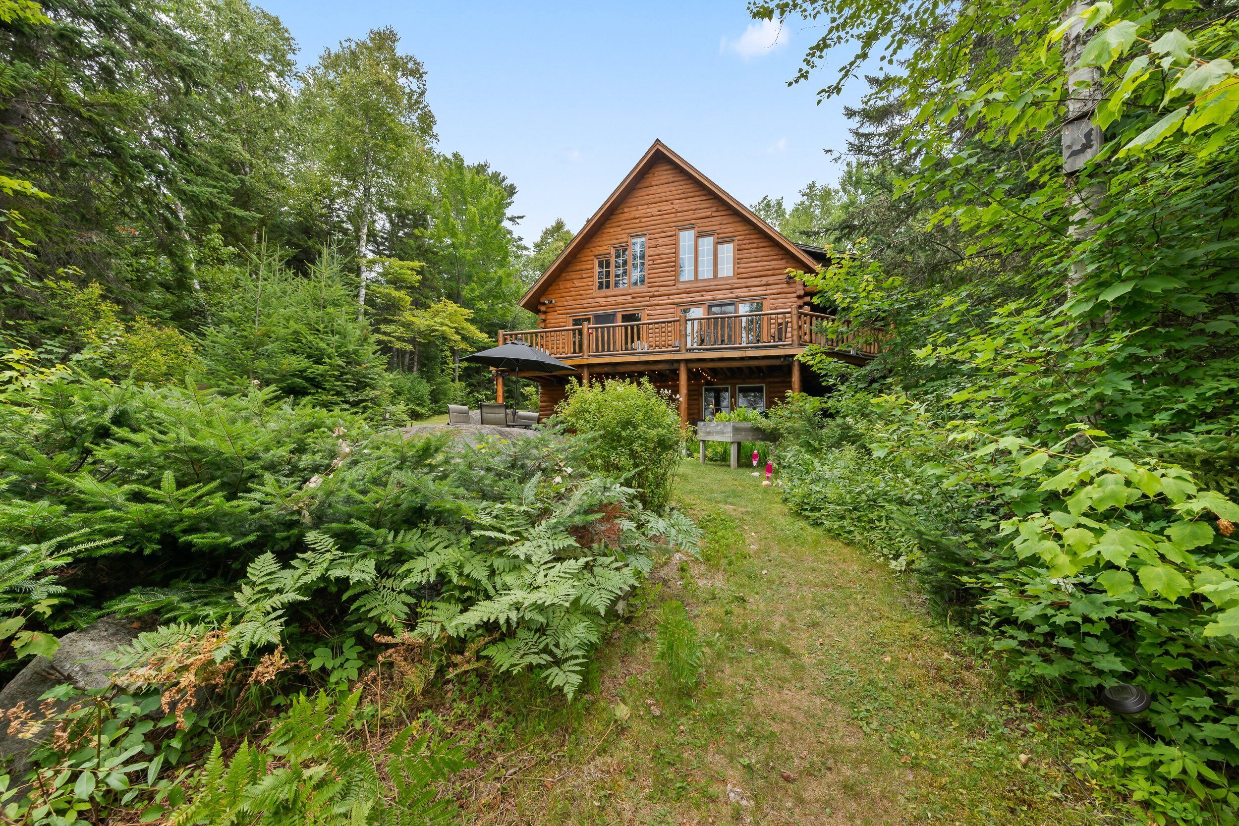 A log cabin with a porch and a covered outdoor seating area.
