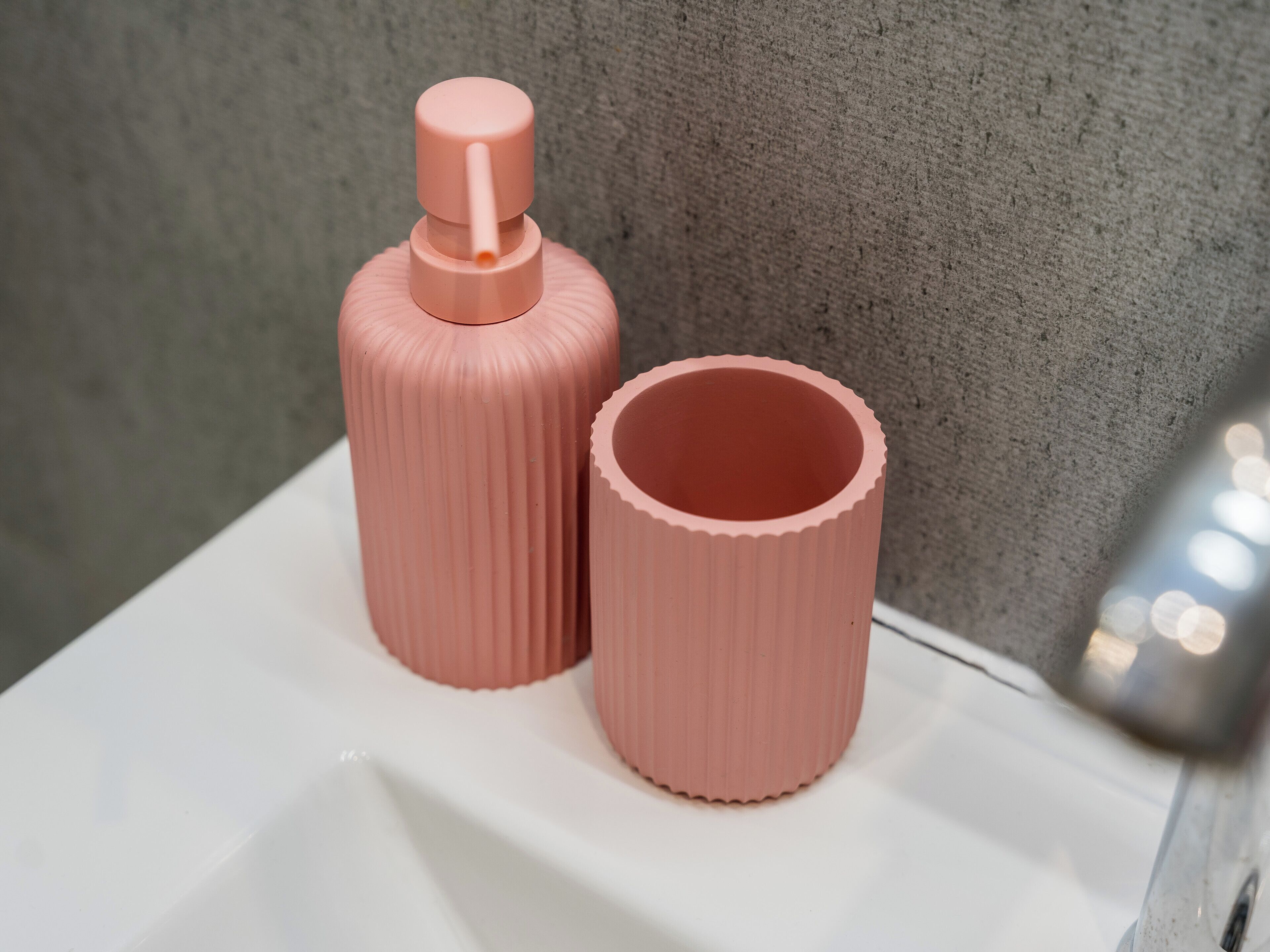 Two pink cylindrical objects on a white surface against a textured wall.