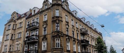 Un edificio histórico con detalles arquitectónicos ornamentales, múltiples balcones y una imponente torre en esquina.