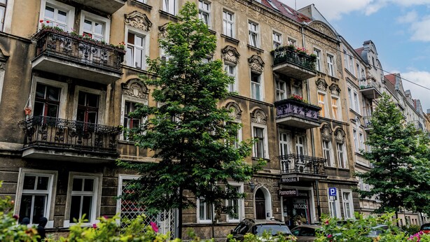 Una hilera de edificios históricos con balcones ornamentales y un cielo azul despejado.