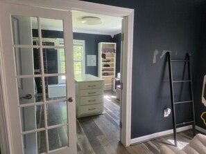 Een kamer met een witte deur, een witte lade en een donkere muur, en een ladder.