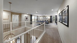 A spacious hallway with a high ceiling, a white railing, and a staircase leading to an upper level. - Spacious 5-bedroom house in amazing Las Vegas with AC (Las Vegas)