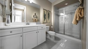 A modern bathroom with a large mirror, white cabinetry, a toilet, and a glass-enclosed shower. - Spacious 5-bedroom house in amazing Las Vegas with AC (Las Vegas)