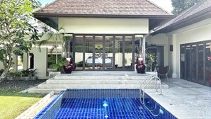 A modern house with a swimming pool, large glass doors, and a tiled roof.