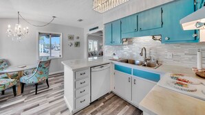 Una cocina moderna con armarios blancos, una pared de acento azul y una araña.