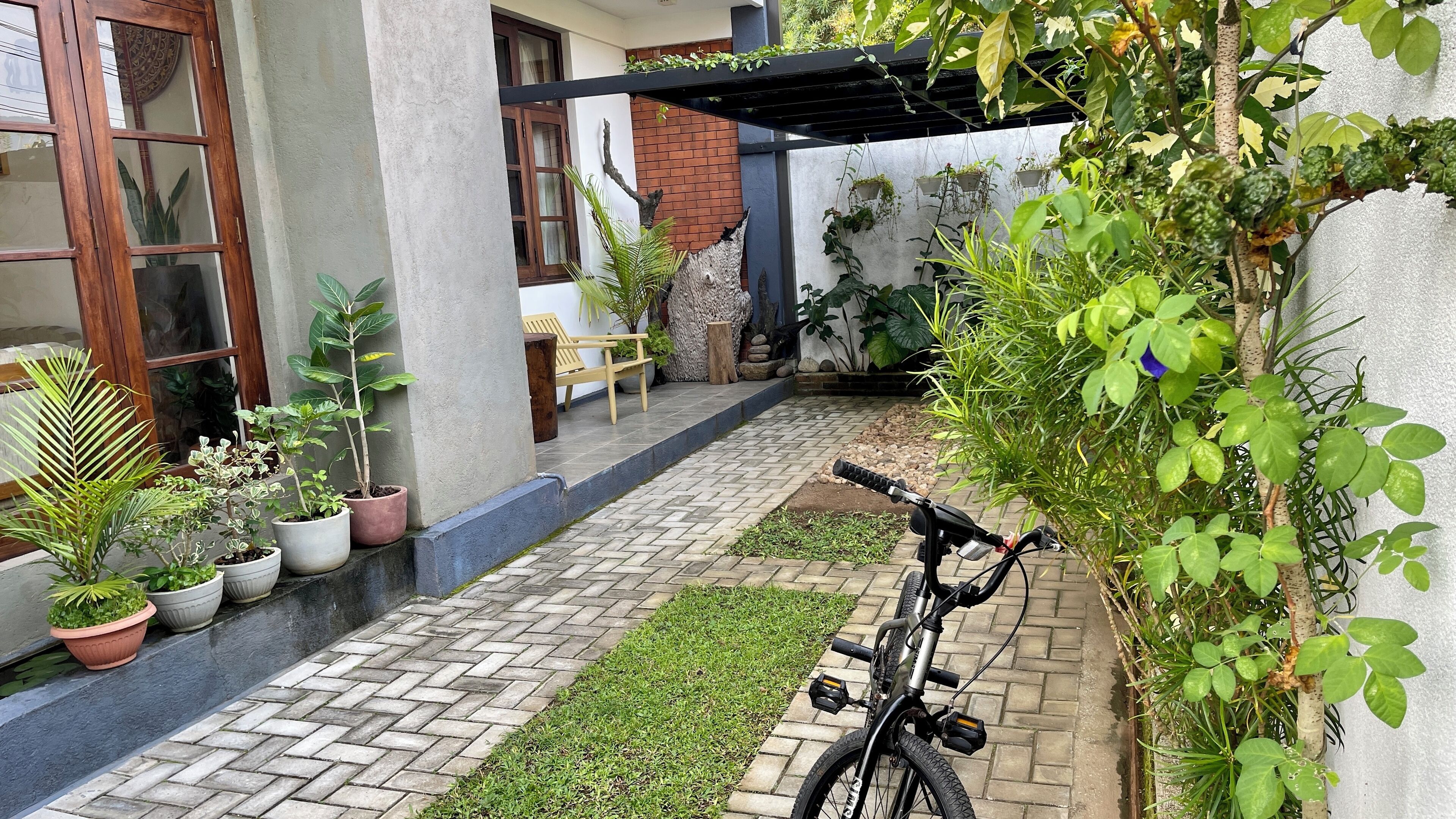 Un patio lastricato con piante in vaso, una bicicletta e una panca di legno.