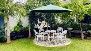 A circular outdoor seating area with a green umbrella, surrounded by lush greenery and potted plants. - Villa in kandy Sri Lanka (Kandy)