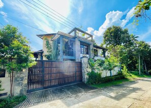 A two-story house with a gated entrance, surrounded by lush greenery and a clear sky. - Villa in kandy Sri Lanka (Kandy)