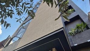 A modern building with a flat roof, large windows, and a mix of brick and concrete materials. - Autenthico Local Stay Hotel Envigado (Envigado)