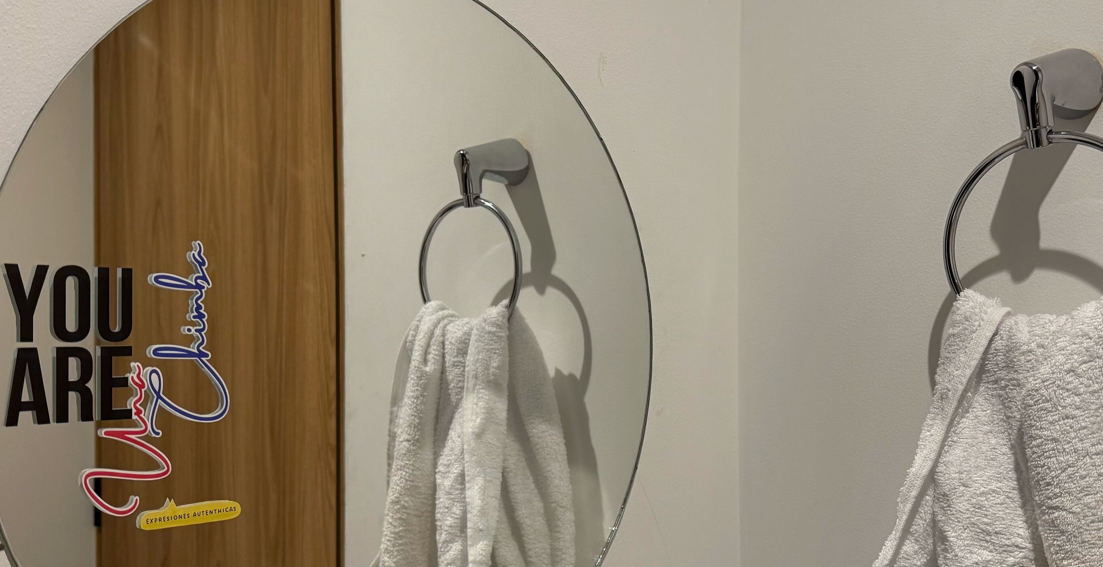 Un baño con puerta de madera y una toalla colgada en un sujetarrollos metálico.