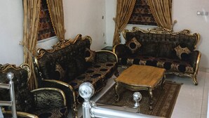 Ein traditionelles Wohnzimmer mit aufwendigen Möbeln, einer Kristallleuchtre und einem dekorativen Spiegel.