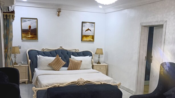 Ein Hotelzimmer mit einem großen Bett, zwei Nachttischen, einem Schreibtisch und zwei Sesseln.