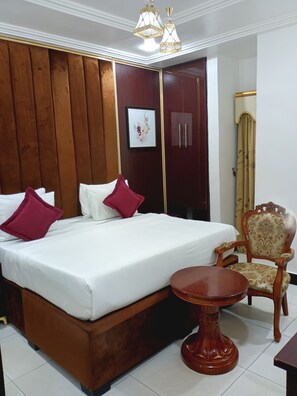 Un dormitorio ordenado con una cama de madera, una silla y una mesita.