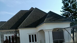 Ein einstöckiges Haus mit Ziegeldach, Kopfsteinpflasterauffahrt und einem kleinen Garten mit Pflanzen.