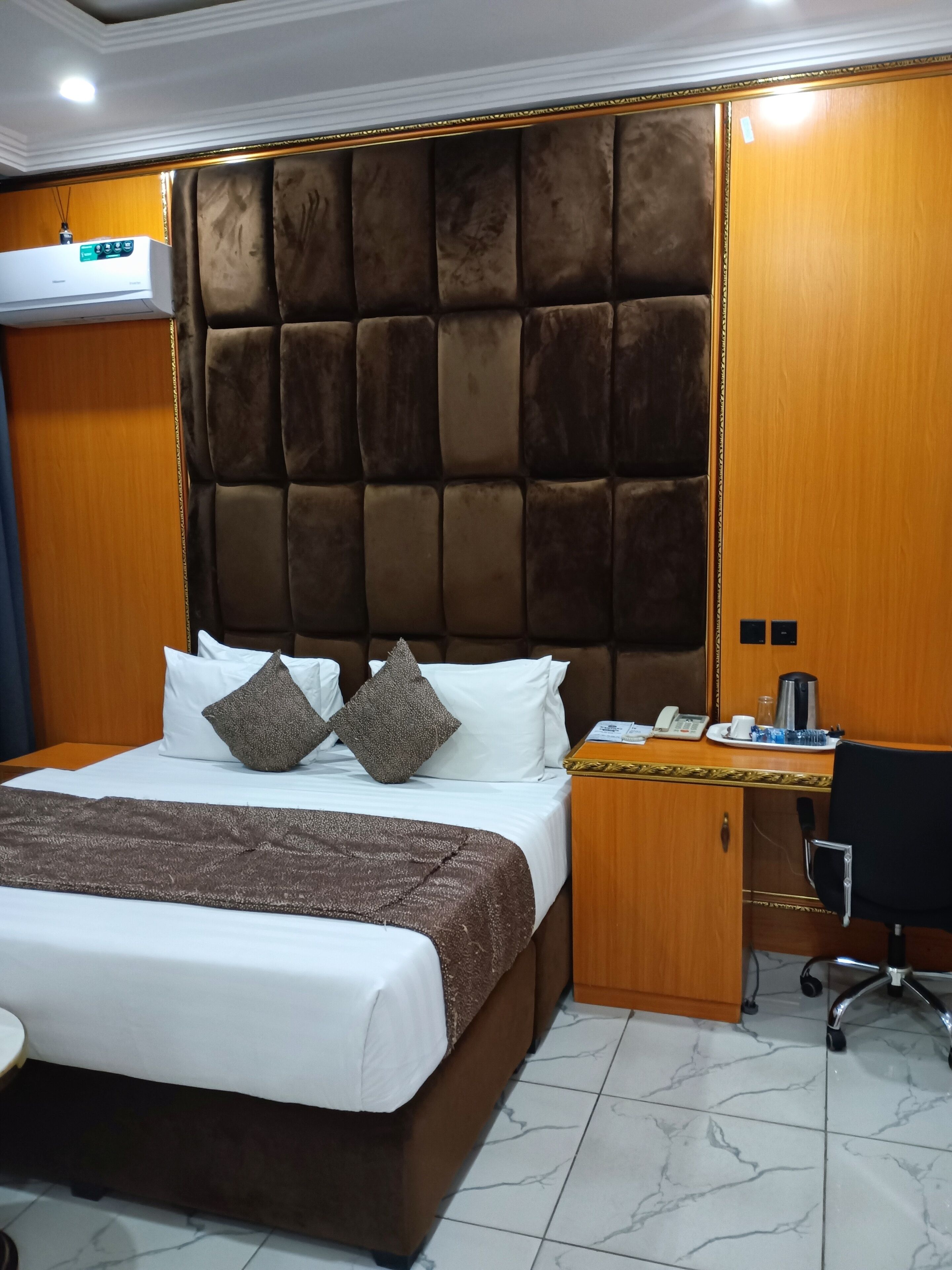 Habitación de hotel con una cama grande, un escritorio de madera, una silla y un minibar.