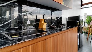 Een moderne keuken met een zwarte marmeren spatwand, houten kastjes en een ingebouwd spoelbak.