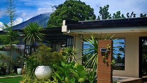 A modern house with a garden, a large decorative globe, and a mountain in the background.
