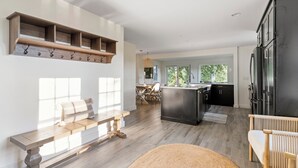 Une cuisine moderne dotée d’un îlot central, d’étagères en bois et d’un coin repas baigné de lumière naturelle.