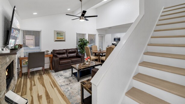 A spacious living area with a fireplace, leather sofa, dining table, and a staircase.
