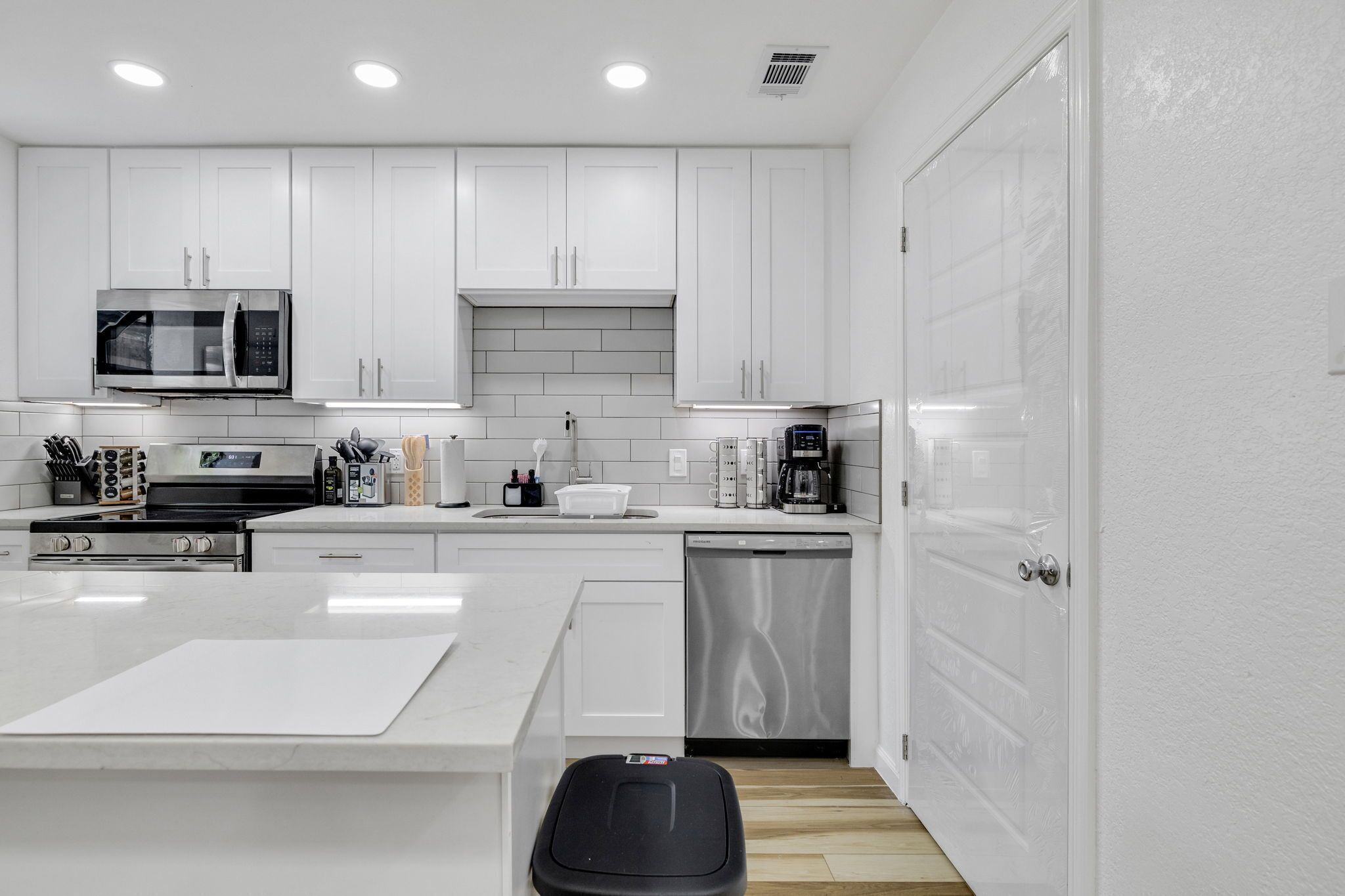 A modern kitchen with white cabinets, a microwave, stove, and dishwasher.