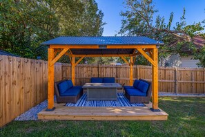 Une terrasse extérieure dotée d’une pergola en bois, d’une table et de sièges rembourrés bleus.