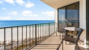 Ein Balkon mit Blick auf Strand und Meer, ausgestattet mit Tisch und Stühlen.