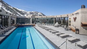 A rooftop pool with lounge chairs and tables, surrounded by glass walls offering mountain views. - Snowbird Ski In/Out Cliff Club w/ private Hot Tub (Snowbird)