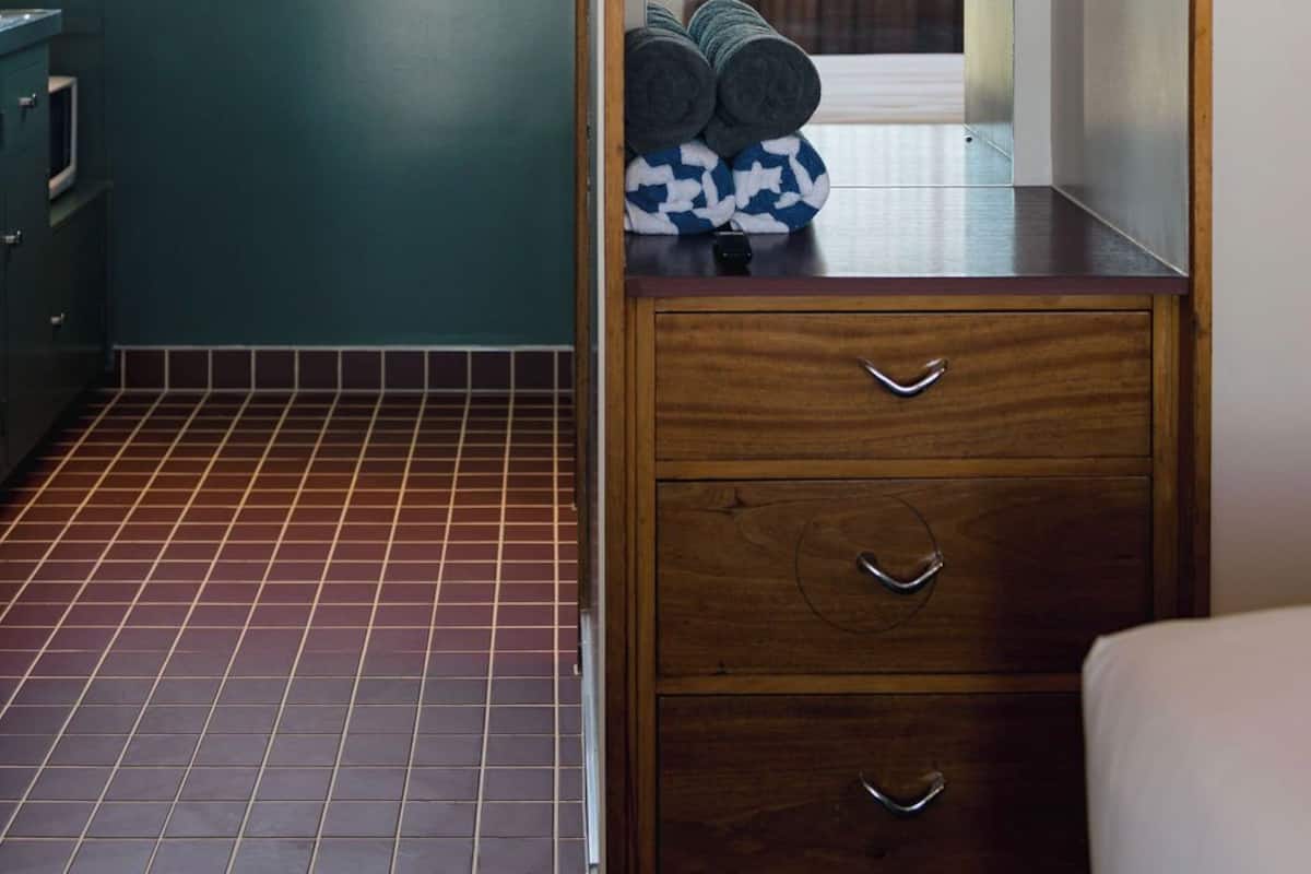 A compact kitchen with a wooden cabinet, a window, and a tiled floor.