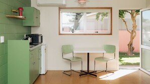 A kitchen with green cabinets, a white countertop, and a window overlooking a backyard. - The Mayfair (Hastings)