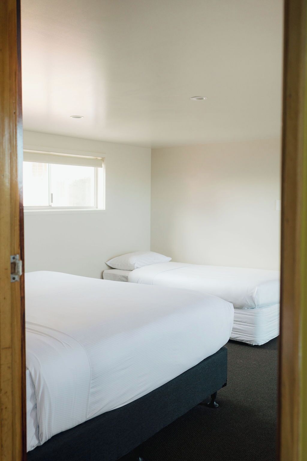 A room with two beds, a window, and a door.