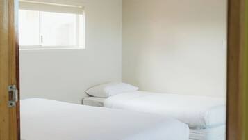 A room with two beds, a window, and a door.