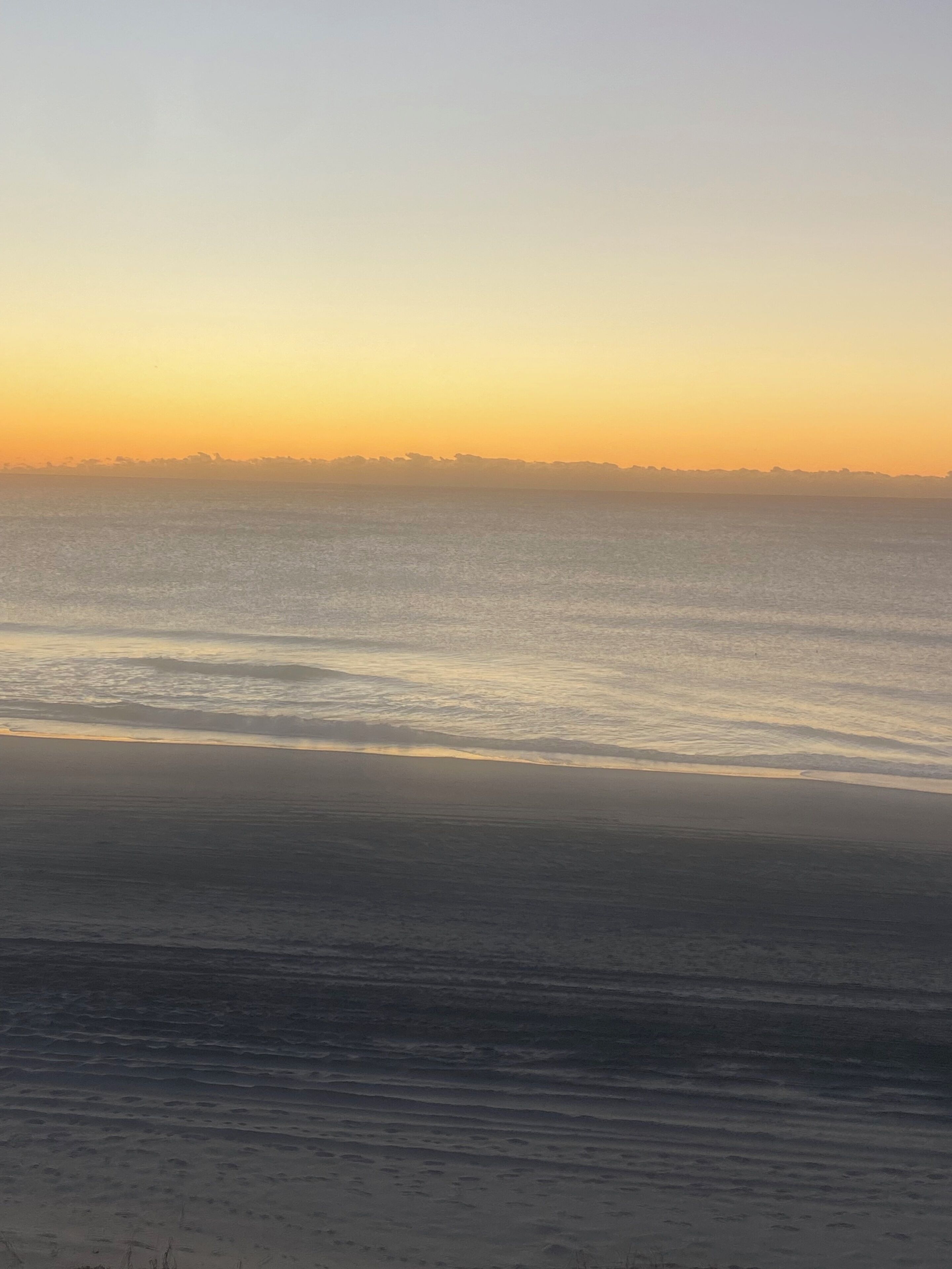 A beach with gentle waves and a clear sky.