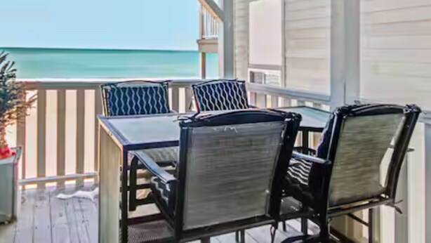 A covered outdoor area with a table and chairs, overlooking a body of water. - Ocean front 3 bedroom- garden city pier (Murrells Inlet)