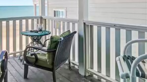 A covered porch with a view of the ocean, a table with chairs, and a railing. - Ocean front 3 bedroom- garden city pier (Murrells Inlet)