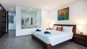 Una habitación de hotel moderna con una cama grande, un muro de cristal y un cuadro en la pared.