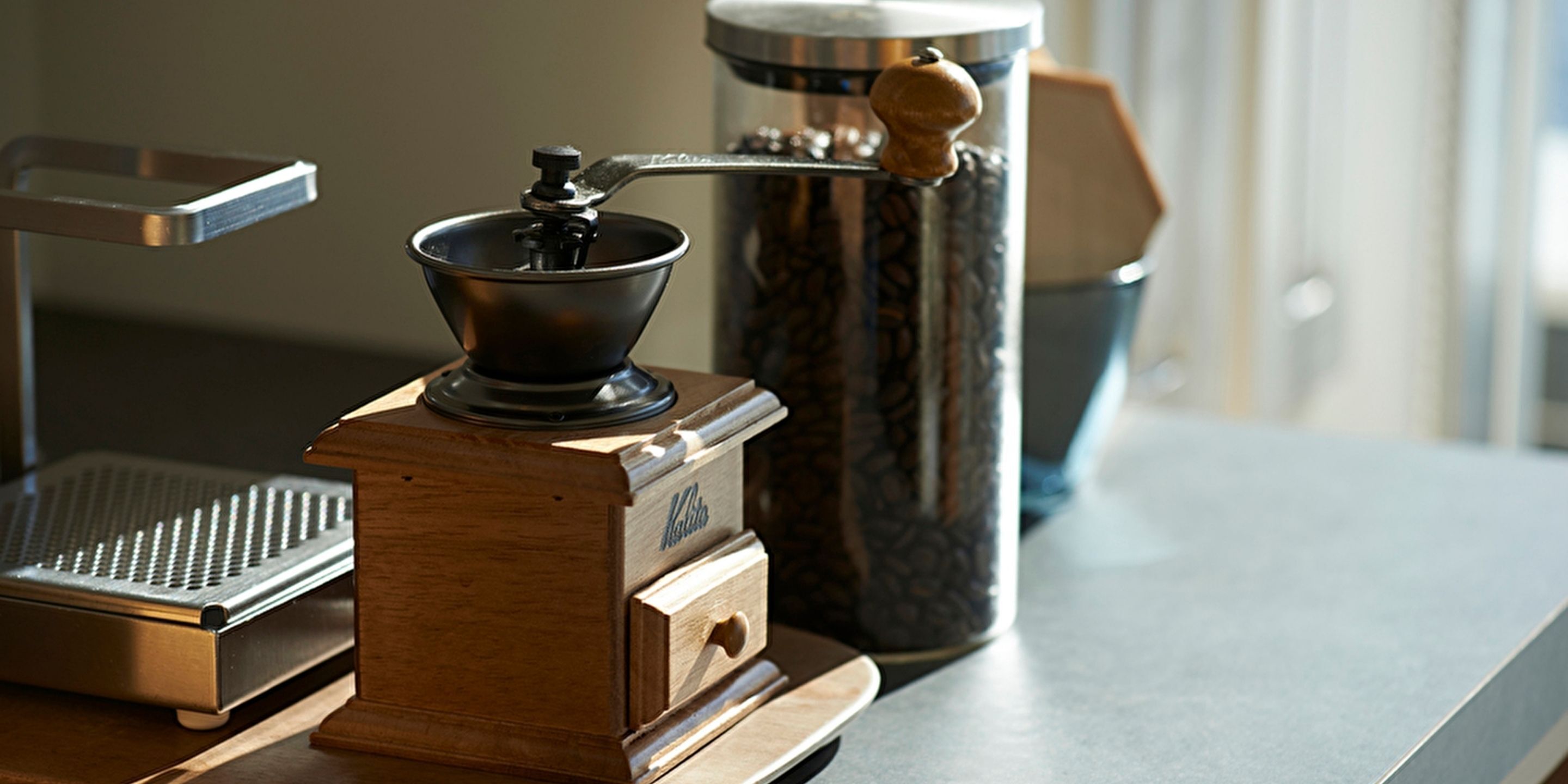 En kaffemaskin placerad på en bänkskiva, tillsammans med en kaffekvarn och en behållare i marmor.