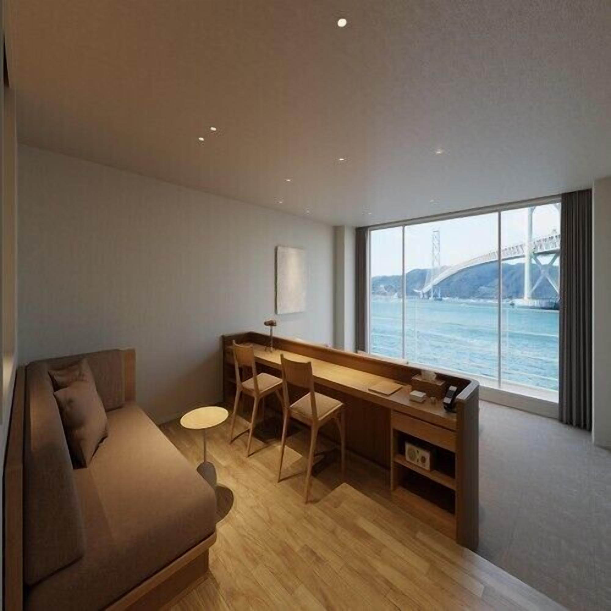 Ein modernes Hotelzimmer mit einer Couch, einem Schreibtisch und Blick auf eine Brücke über dem Wasser.