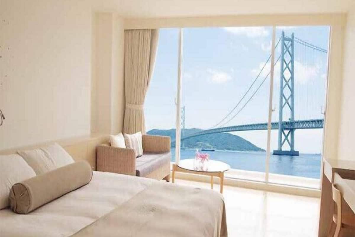 Une chambre d’hôtel avec un grand lit, un canapé, une petite table et une vue sur un pont.