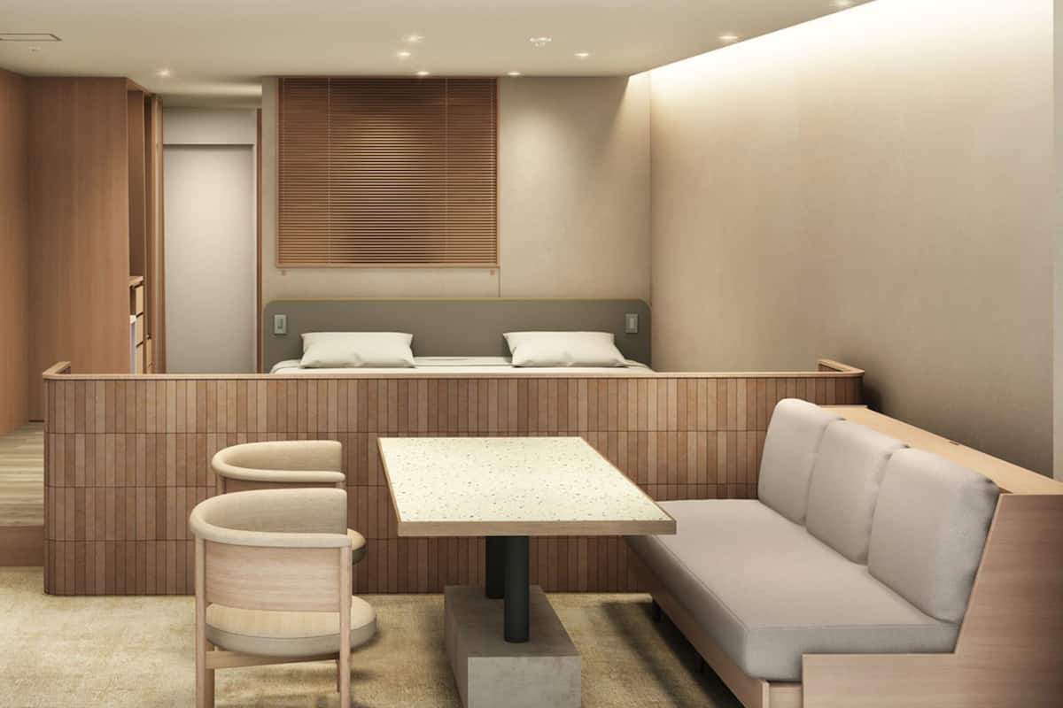 Une chambre moderne et compacte, comprenant un lit, une petite table, un banc et un meuble de rangement.