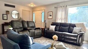 A living room with two leather sofas, a blue armchair, a coffee table, and a vase with a flower. - Near Lake Michigan- Weko Beach | Private Setting | Beach Gear (Bridgman)