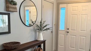 A hallway with a wooden console table, a mirror, a potted plant, and a white door. - Near Lake Michigan- Weko Beach | Private Setting | Beach Gear (Bridgman)