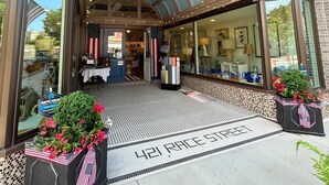 A hotel entrance with a glass canopy, a welcome mat, and American flags. - Station House East: Upscale Loft in the Historic District Cambridge, MD (Cambridge)