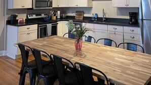 A modern kitchen with white cabinets, a wooden dining table, and black chairs. - Station House East: Upscale Loft in the Historic District Cambridge, MD (Cambridge)