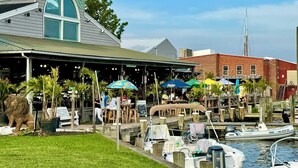 A waterfront restaurant with outdoor seating, a marina with boats, and a building with a green awning. - Station House East: Upscale Loft in the Historic District Cambridge, MD (Cambridge)