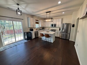 A modern kitchen with white cabinets, stainless steel appliances, and a central island with bar stools.