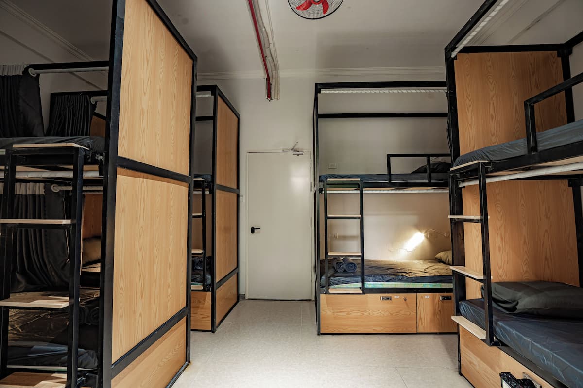 A dormitory room with bunk beds, a wardrobe, and a desk.